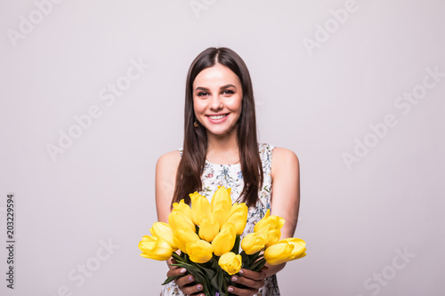 Young portrait of woman with flowers yellow tulips in hands on a light background photo