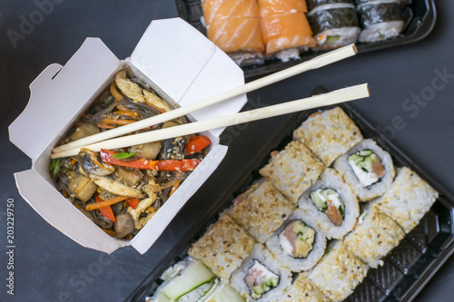 Delivery of a hot lunch in a box. Lapshi with chopsticks on the background of rolls. photo