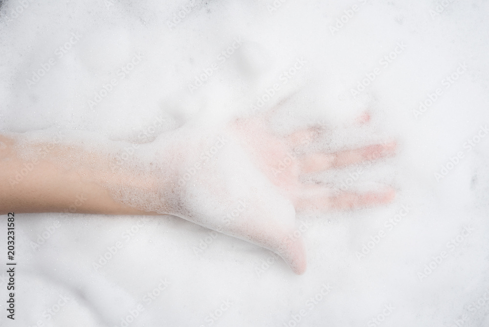 Fototapeta premium Hand female with soft foam bubble from soap or shampoo washing on top view