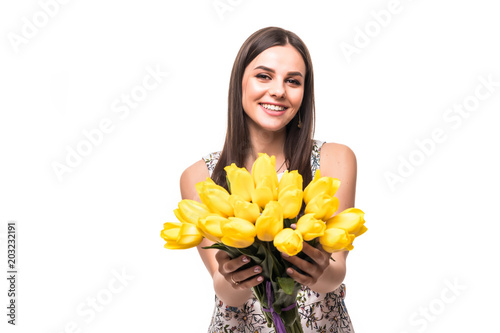 Spring time. Young portrait of woman with flowers yellow tulips in hands on a light background photo