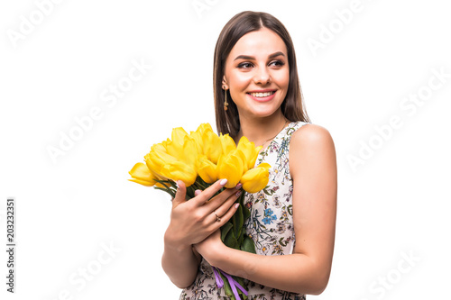 Young portrait of woman with flowers yellow tulips in hands on a light background photo
