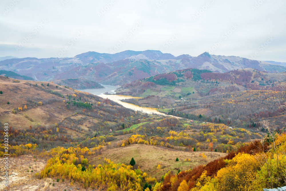 Mountain landscape with colorful trees, Toxic river with multi-colored water - yellow, grey, turquoise. Drowned village next to gold mine in countryside, in Rosia Montana, Romania.