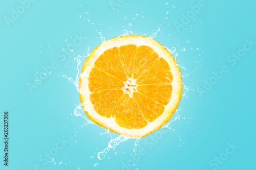 Fresh orange slice with water splash on blue background