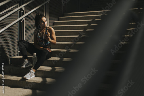 Young female runner resting on stairs