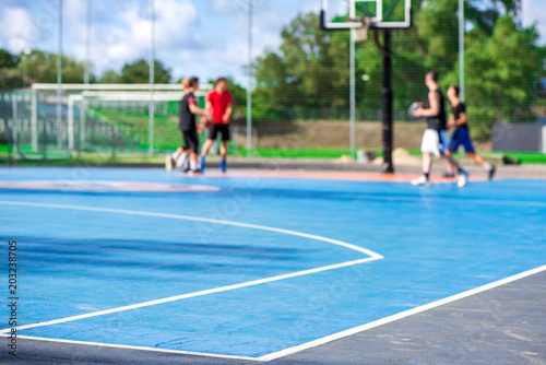 Abstract, blurry background of boys playing basketball in outdoor basketball court in park