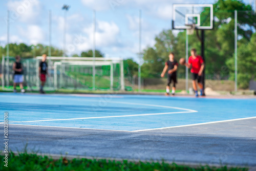 Abstract, blurry background of boys playing basketball in outdoor basketball court in park © lainen