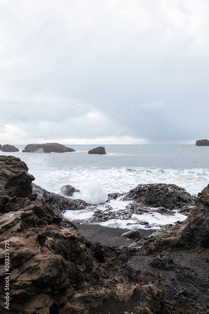 White surf and ocean waves crashing onto rocky shore Iceland