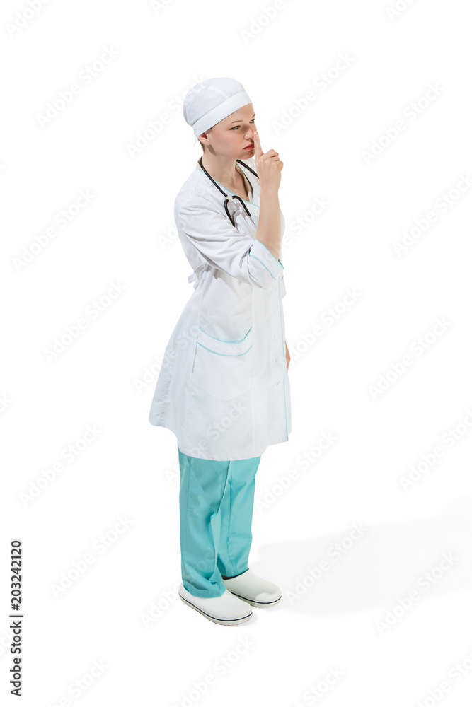 Beautiful young woman is whispering a secret in white coat posing at studio. Full length studio shot isolated on white. Beautiful young woman is whispering a secret in white coat posing at studio. Full length studio shot isolated on white.