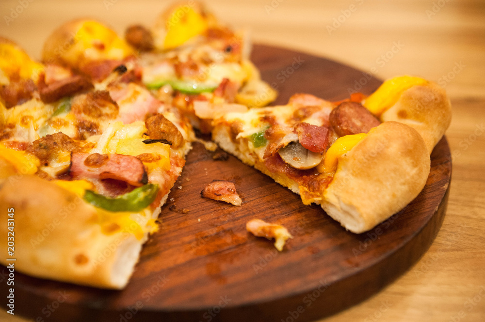 ham and pepper pizza lay on wooden plate,delicious pizza put on wooden plate,Pizza is being eaten,selective focus