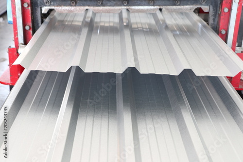 zinc coated metal sheet roof rolled from rolling machine made from coiled steel ; industry equipment background