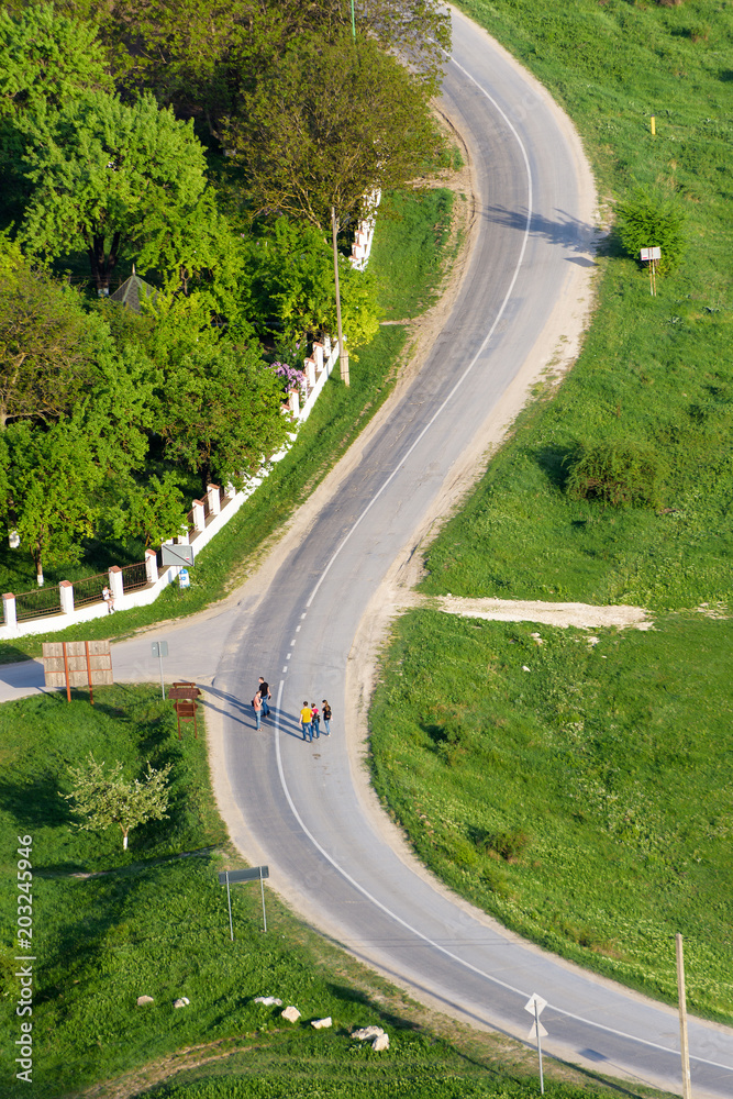 People crossing a winding s curved road in Trebujeni village