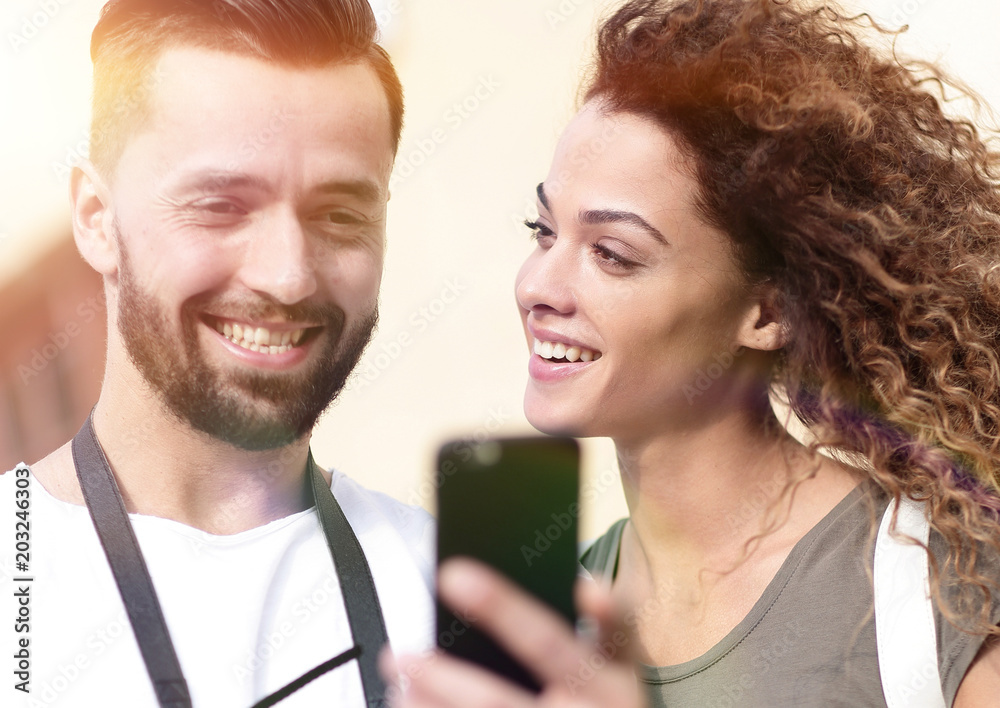 Happy young couple searching for location both on mobile phone Happy young couple searching for location both on mobile phone