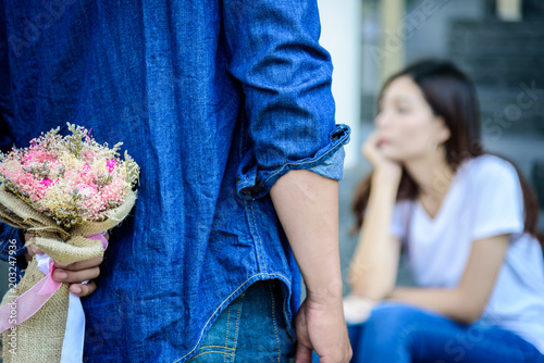 Asian man has preparing and waiting with flower for say sorry and apologies to girlfriend. photo