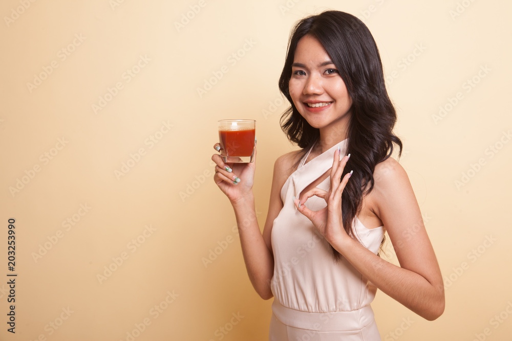 Young Asian woman show OK with tomato juice. Young Asian woman show OK with tomato juice.