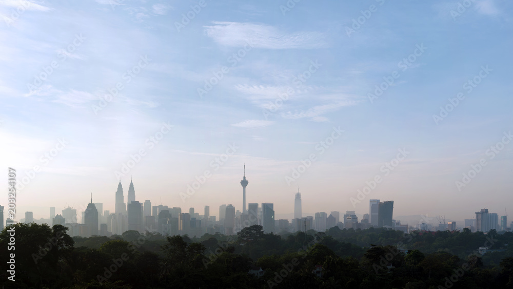 Fototapeta premium panorama view of beautiful kuala lumpur cityscape skyline in the hazy or foggy morning enviroment and buildings in silhouette with copy space