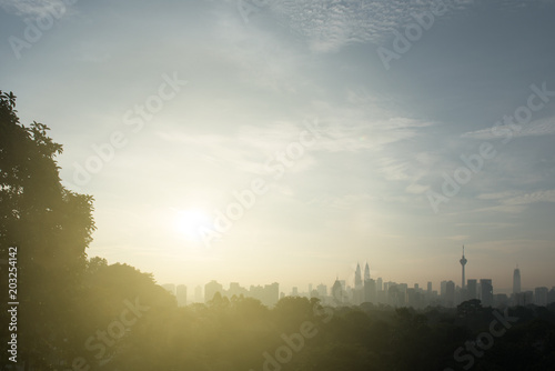 Beautiful kuala lumpur cityscape skyline and surrounding nature with hazy or foggy morning sunshine. silhouette buildings and trees. nature and development concept