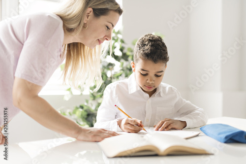 mother help Black boy doing homework at home