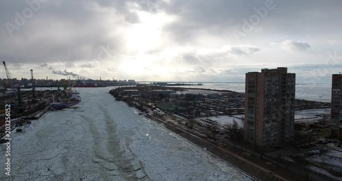 Flying over cargo port. The tugboat moving through an ice. Aerial drone footage
