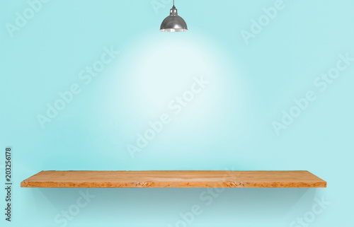 Wooden shelf with lamp on blue vintage wall.