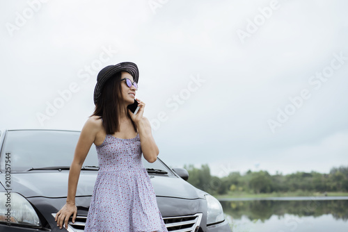 Asia woman standing next to car using smart phone