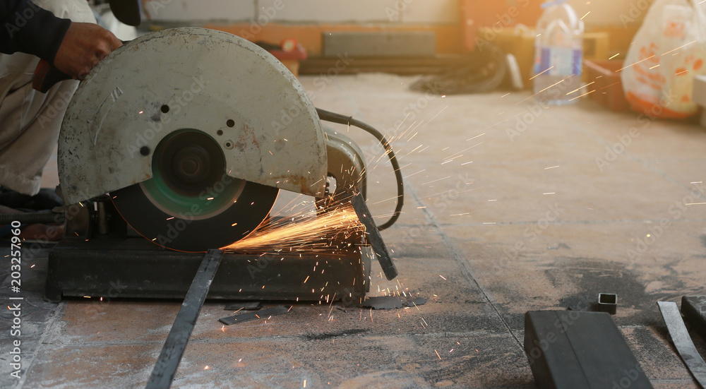 Close-up of worker cutting metal with grinder. Sparks while grinding iron. Close-up of worker cutting metal with grinder. Sparks while grinding iron.