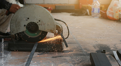Close-up of worker cutting metal with grinder. Sparks while grinding iron.