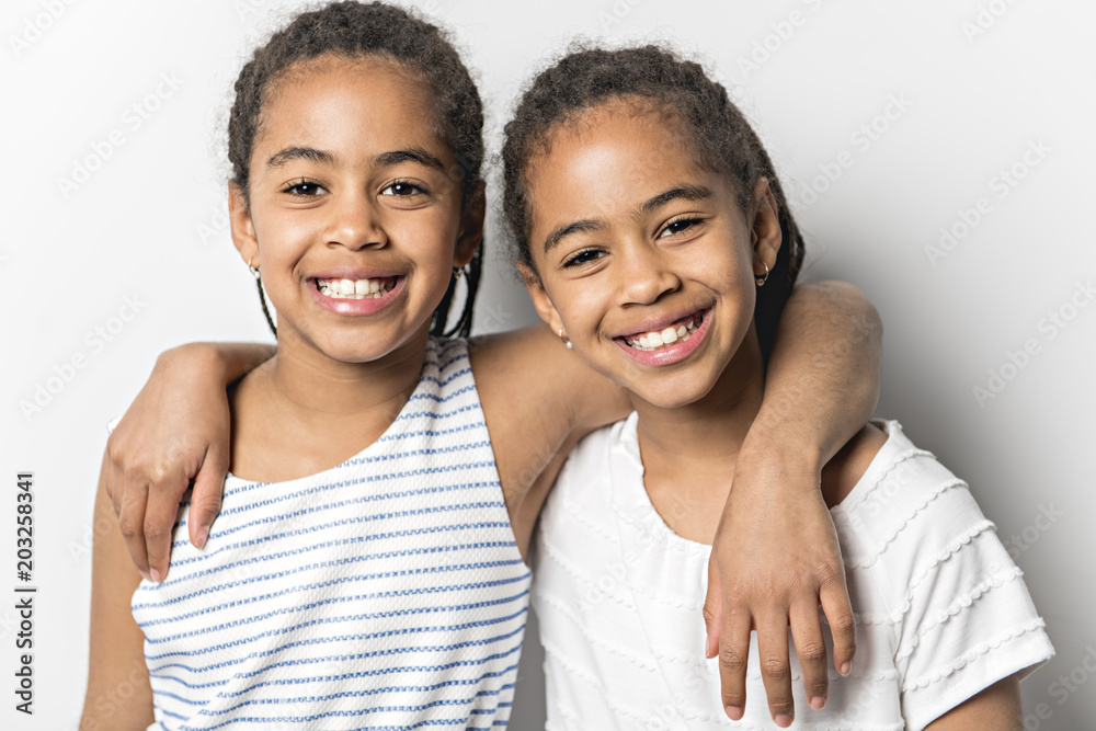 Adorable african twin little girls on studio gray background Adorable african twin little girls on studio gray background