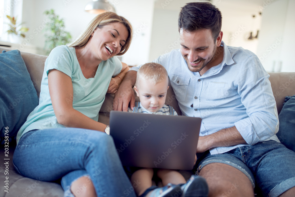 Happy family using laptop together on sofa Happy family using laptop together on sofa
