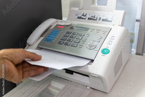 Hand Man are using a fax machine in the office. Business concept  photo