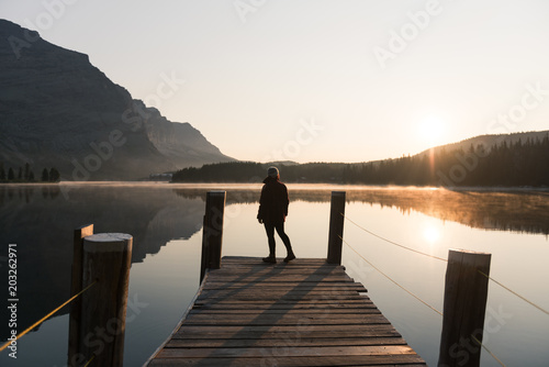 Woman looking out at lake on pier, West Glacier, Montana, USA