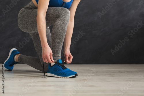 Woman tying up lace on sport shoes closeup