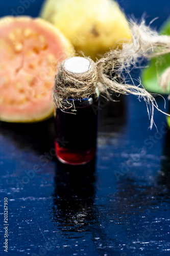 Red colored Floral and fruit essence of Guava or Jamrudh or Psidium guajava or common red guava with its fresh leaves and organic fruit on black wooden surface. photo