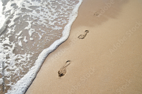 Footprints in the sand and a wave