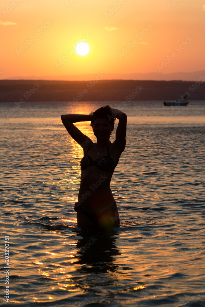 Silhouette of a woman in the sea at sunset
