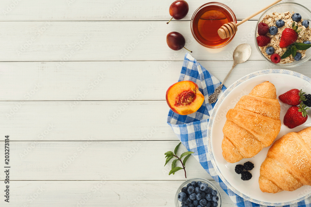 Continental breakfast with croissants and berries on white wood Continental breakfast with croissants and berries on white wood
