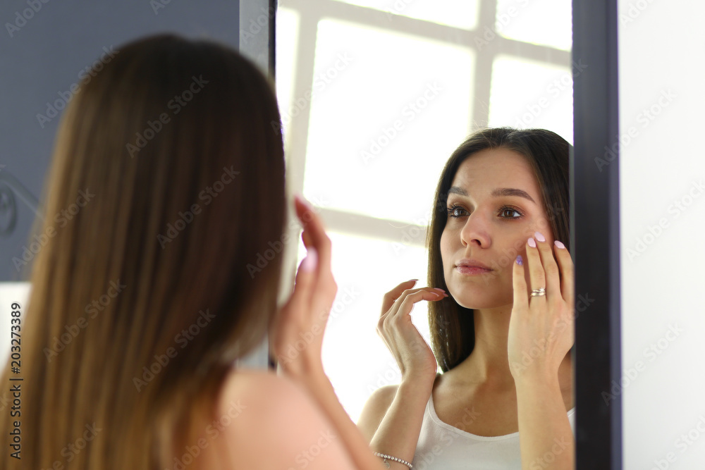 Young woman looking herself reflection in mirror at home Young woman looking herself reflection in mirror at home