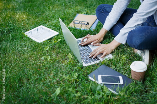 Busy freelancer girl working with laptop in the park during the day