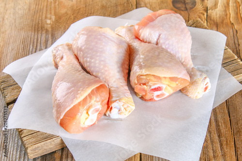 Quadro su tela Raw chicken legs on a cutting board on an old wooden table.