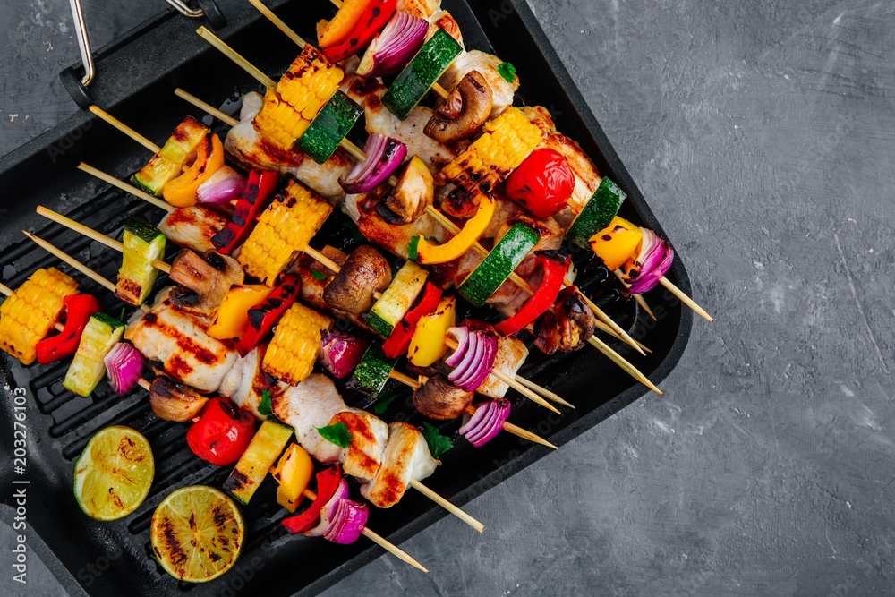 Grilled vegetable and chicken skewers on a grill pan, top view