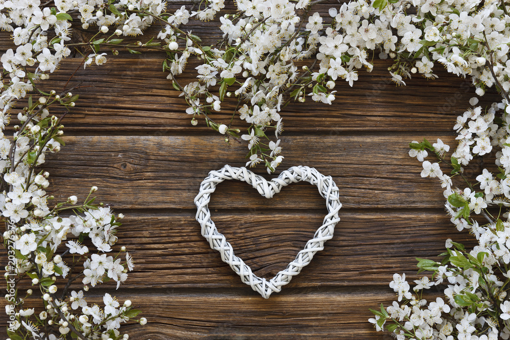 Close-up photo of Beautiful white Flowering Cherry Tree branches with white heart shape. Wedding, engagement or betrothal concept on vintage wooden background. Top view, greating card. Close-up photo of Beautiful white Flowering Cherry Tree branches with white heart shape. Wedding, engagement or betrothal concept on vintage wooden background. Top view, greating card.