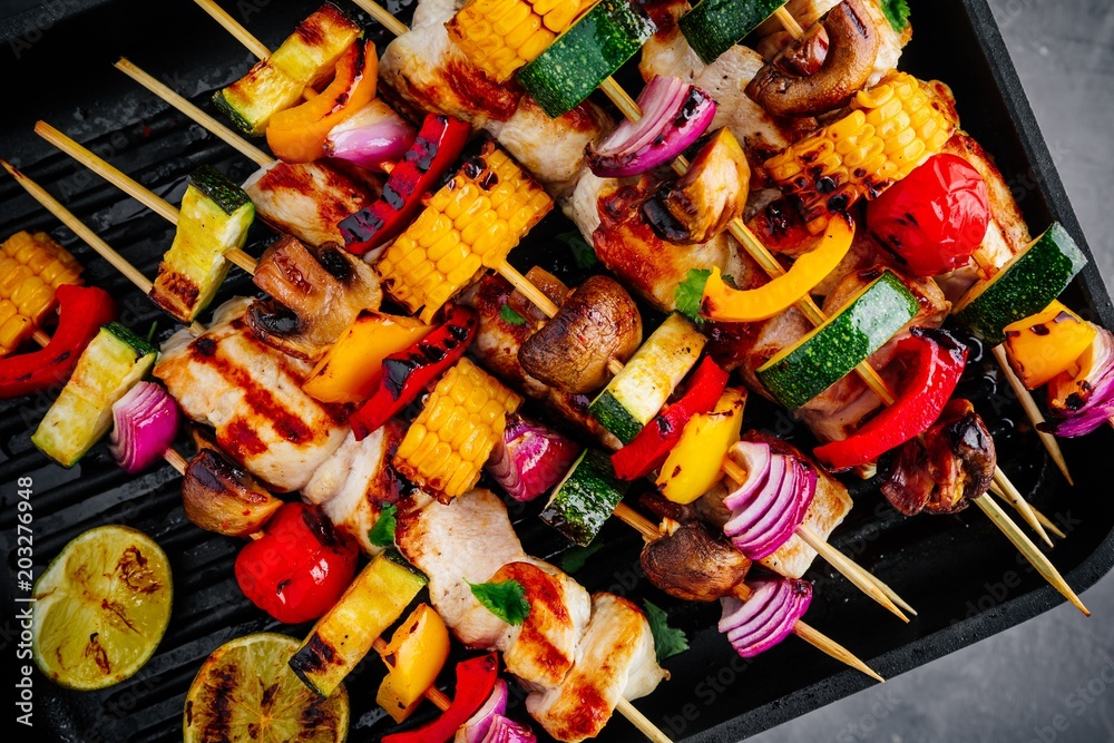 Grilled vegetable and chicken skewers on a grill pan, top view