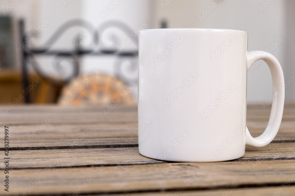 White blank coffee mug mock set-up, outside on a little wooden table with  an ironwork