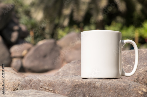 White blank coffee mug mock up, close-up of mug outside in the sunshine on some large decorative garden stones.	Perfect for businesses selling mugs, just overlay your quote or design on to the image.