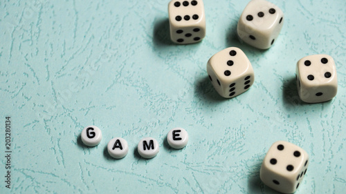 The word  Game  is composed of multicolored wooden letters and game dice on a mint background.