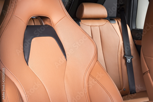 Part of red leather car seat with the unfocused car interior on the background © gargantiopa
