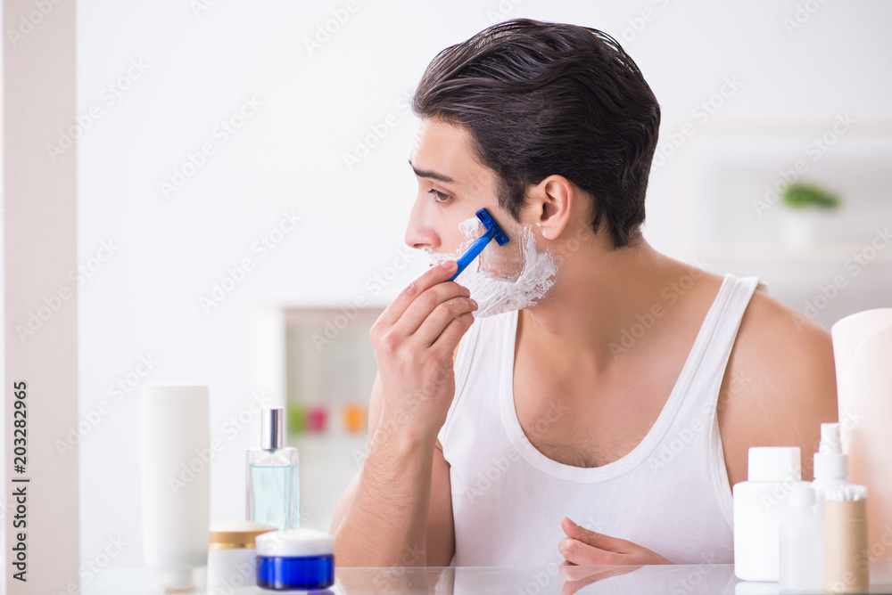 Young handsome man shaving early in the morning at home Young handsome man shaving early in the morning at home