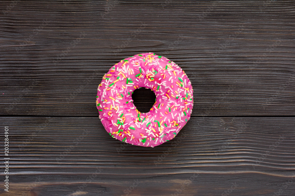 Pink donut on brown wooden background. Top view. Close-up