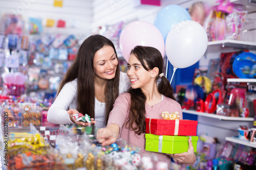 Smiling female and girl with gifts and balloons in the candy store