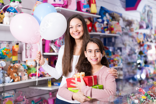 smiling woman and daughter with gifts and balloons in the shop