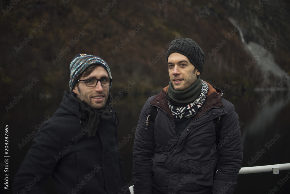 Hombres jóvenes con gorro de invierno frente a fiordos noruegos